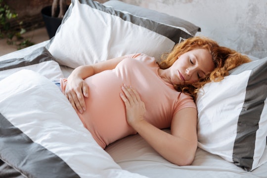 A pregnant woman on bed rest lying in bed 