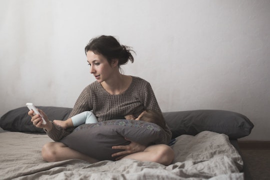 Woman sitting on her bed breastfeeding her baby