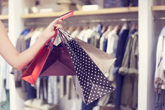 A hand holding four shopping bags at a 4th of July sale