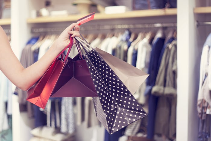 A hand holding four shopping bags at a 4th of July sale