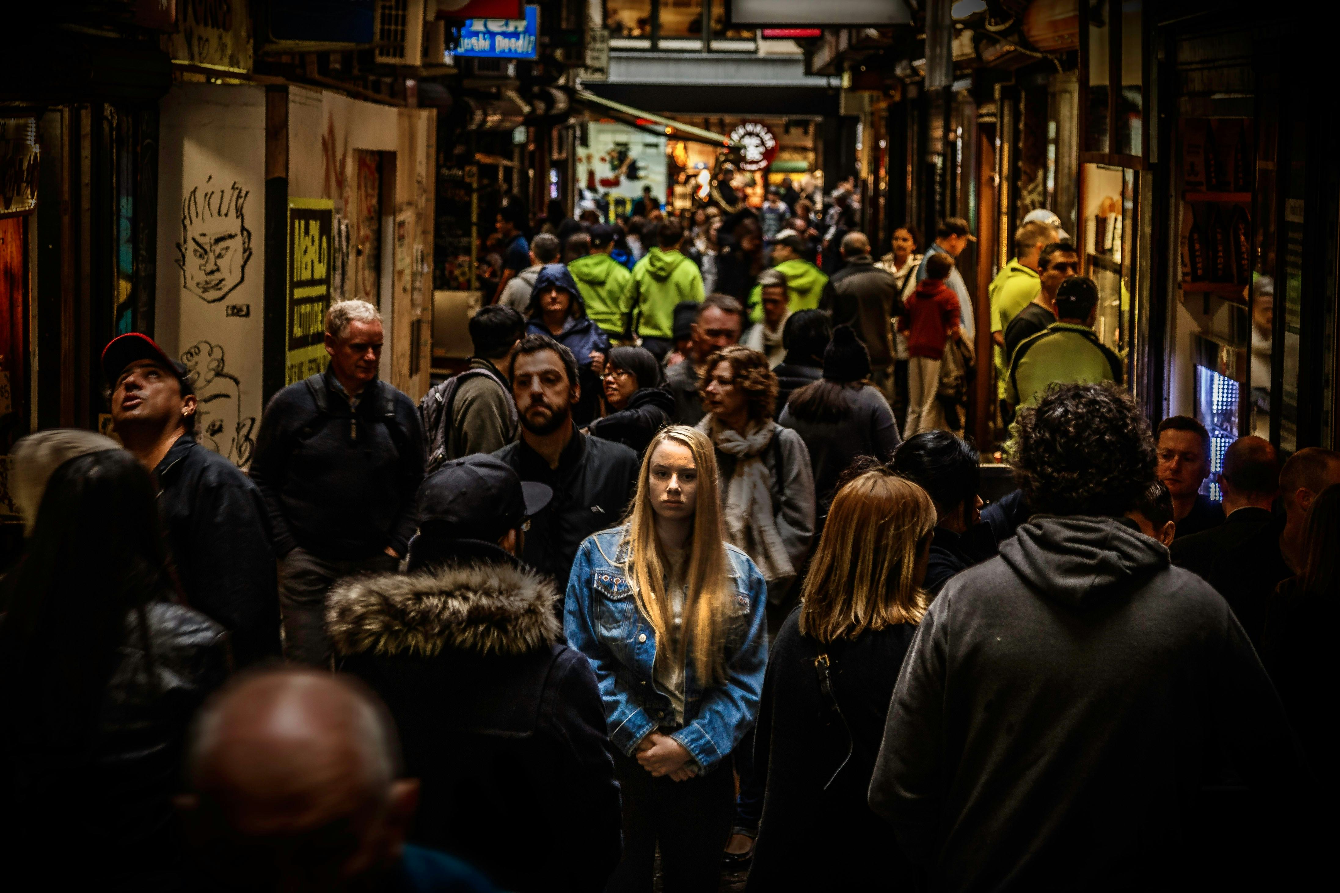 A woman in a blue jacket standing in a crowd while facing her social anxiety