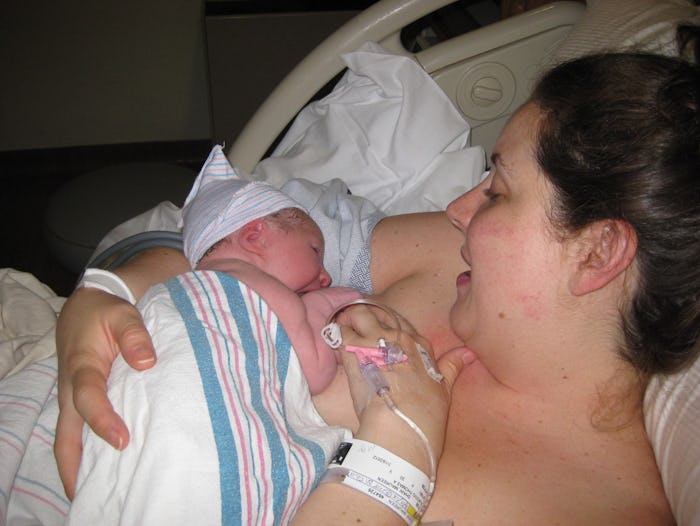 A mother lying in a hospital bed with her newborn baby