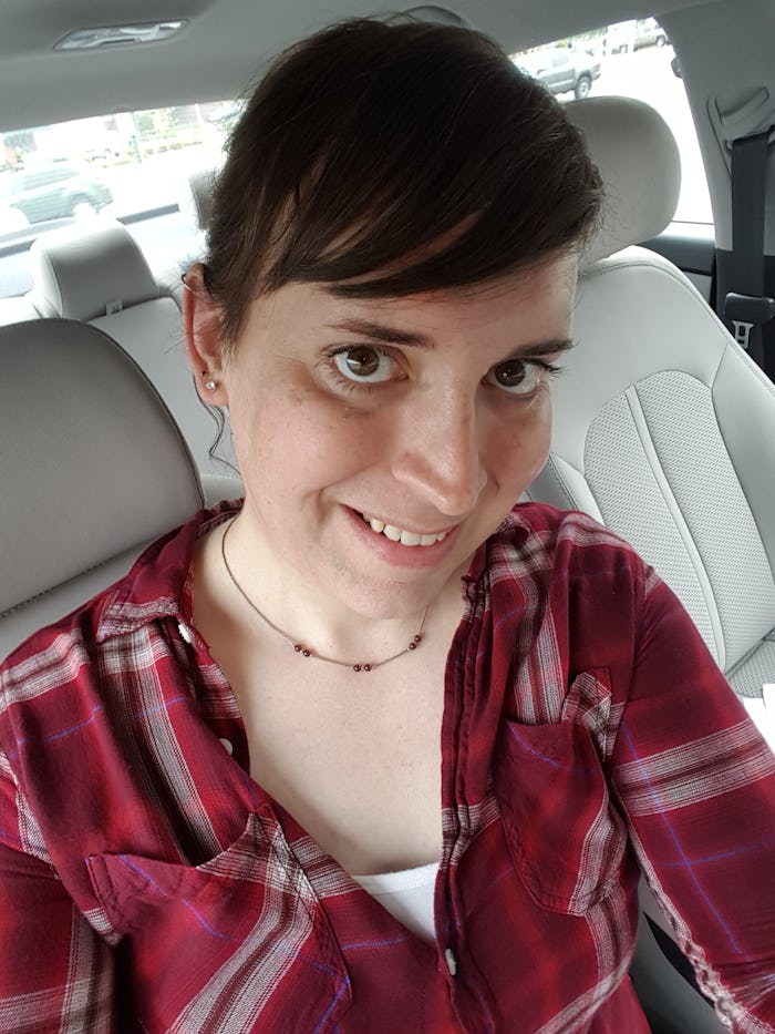 Katelyn Burns sitting in her car in a red button up shirt smiling while taking a selfie