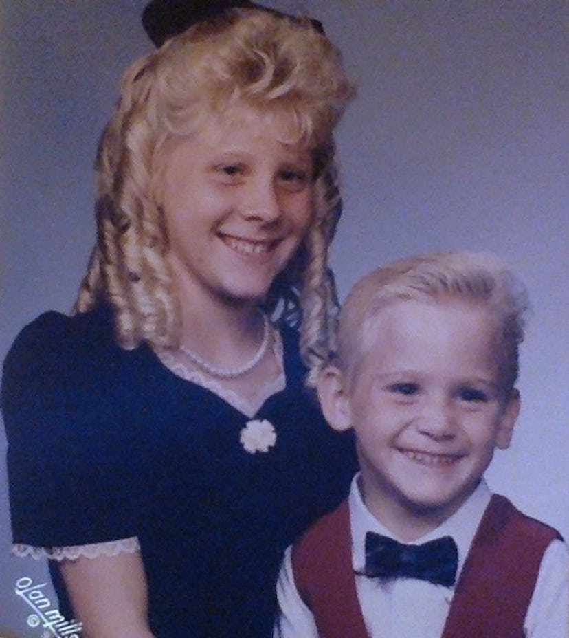 An old picture of a young girl and a little boy dressed formally for a family photoshoot.