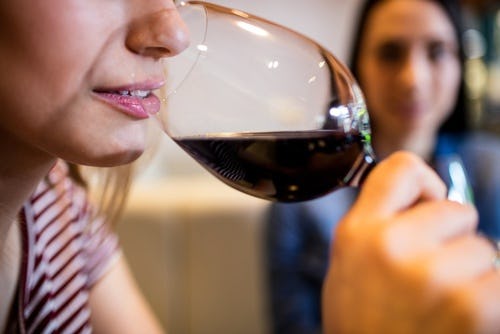 A mom putting her wine glass to her nose and sniffing the wine