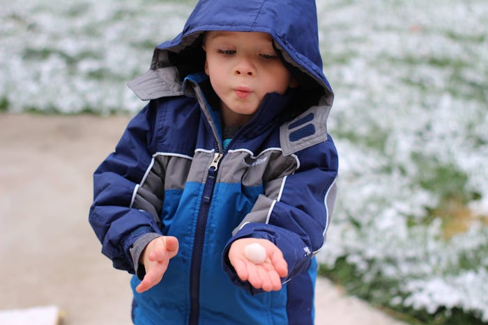 A boy who is raised using the Reggio Emilia method, wearing a blue jacket outside
