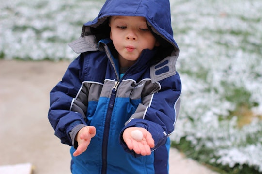 A boy who is raised using the Reggio Emilia method, wearing a blue jacket outside