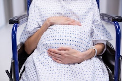 Pregnant woman in labor, sitting in wheelchair at hospital 