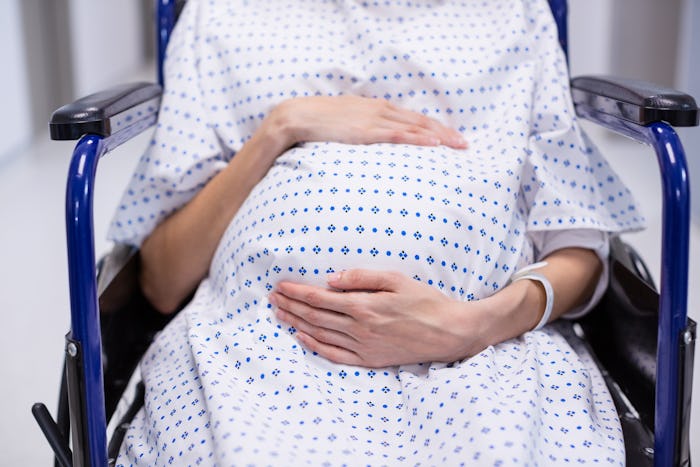 Pregnant woman in labor, sitting in wheelchair at hospital 