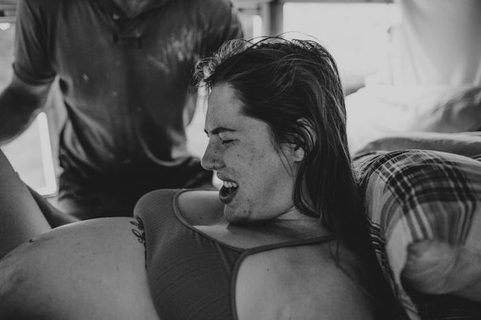 A black and white photo of a woman giving birth on a school bus