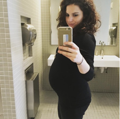 EJ Dickson talking a selfie in a mirror while being pregnant, wearing a black dress