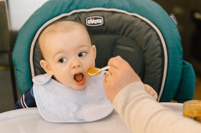 A baby having its first taste of baby food