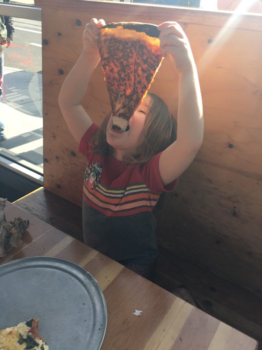 Elle Stangers' kid eating a large piece of pizza