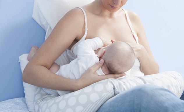 A lady laying in her bed and breastfeeding her little baby