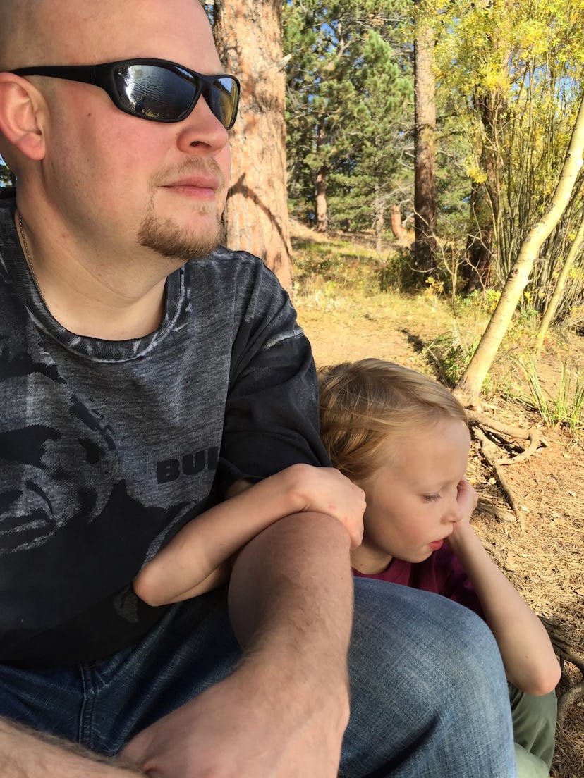 A father wearing sunglasses, sitting with his child in the park