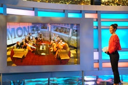 A woman next to a large screen during a temptation competition on 'BB19'