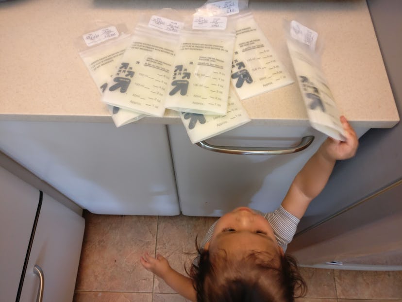 Child reaching for milk bags on bench.