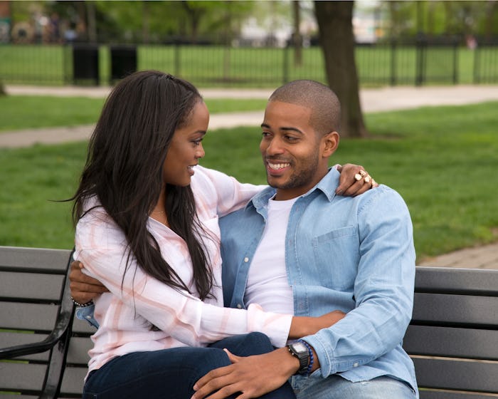 Eric from the 'Bachelorette' sitting on a bench next to a woman that is hugging him
