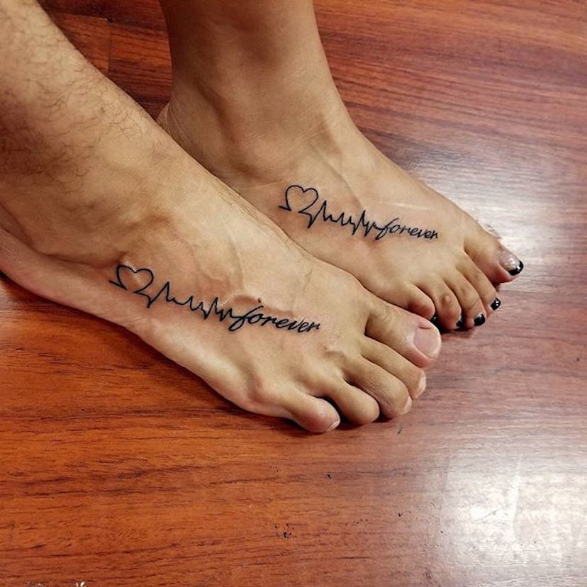 Man and woman with matching heart beat line with text tattoos on their feet
