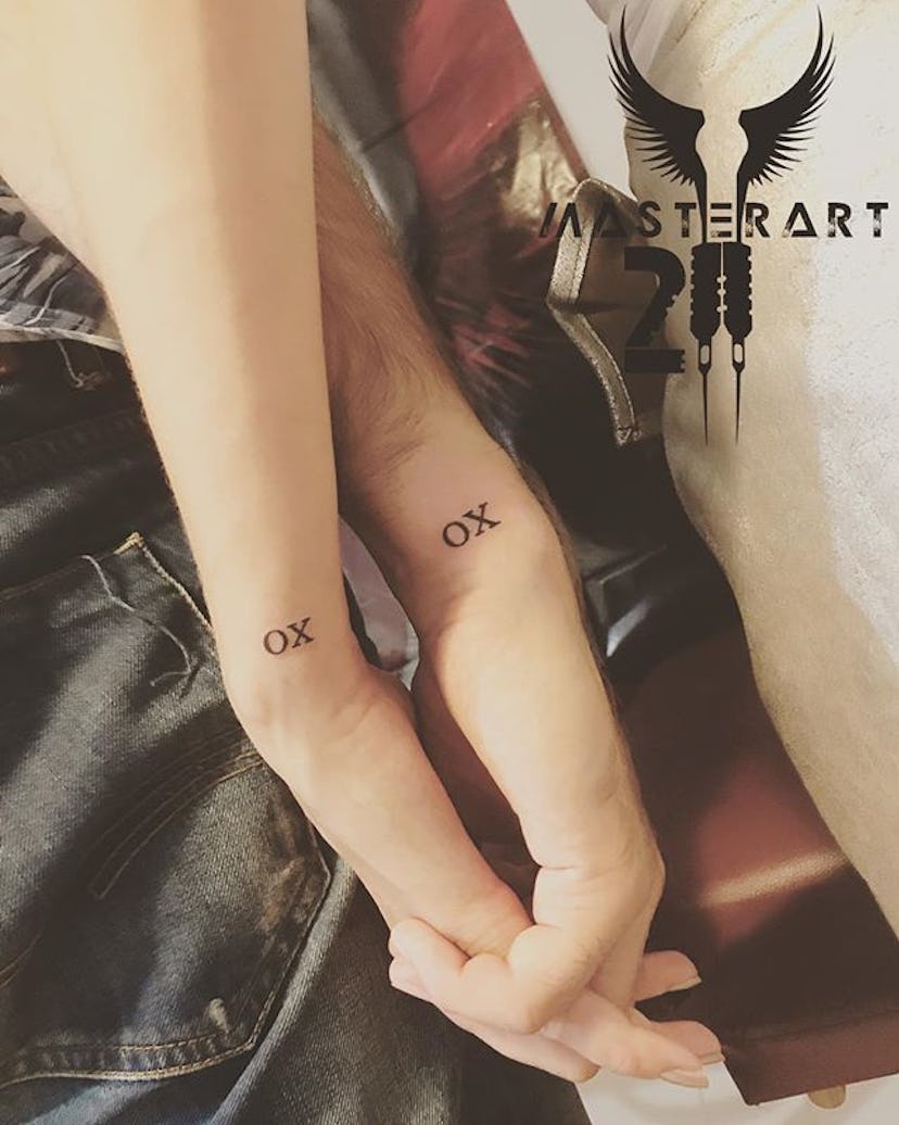 Man and woman with matching XO tattoos on their wrists