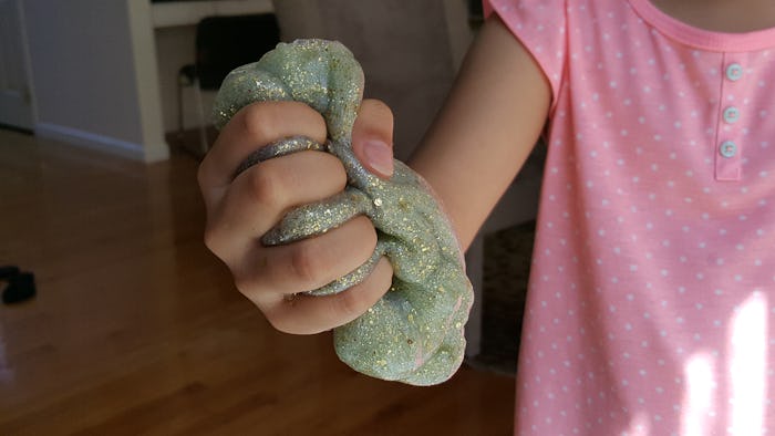 close up of kid holding glittery green slime 