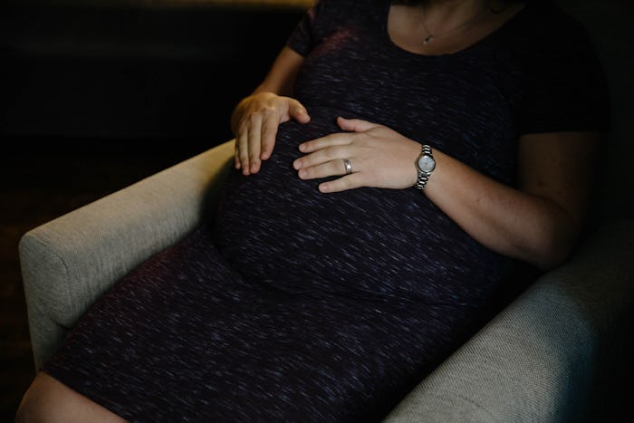 A pregnant woman sitting with her hand on her stomach, who has had Preeclampsia before