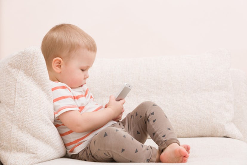 A toddler boy looking at the phone