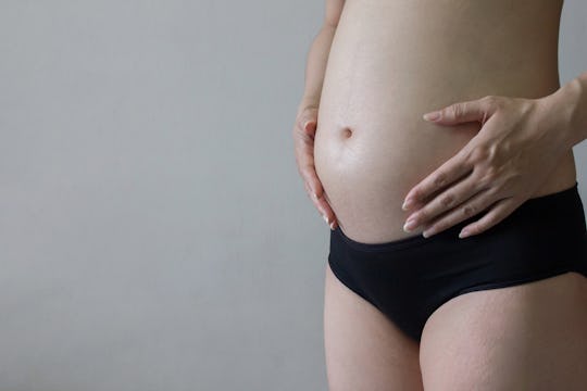 Pregnant woman in underwear  massaging her tummy