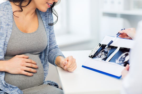 Pregnant woman holding her hand on her tummy while in the doctor's office