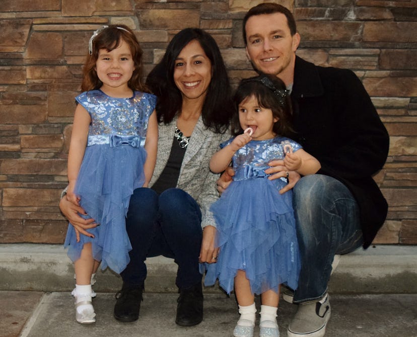 A happy family of four, with daughters being in same outfit, posing for the picture