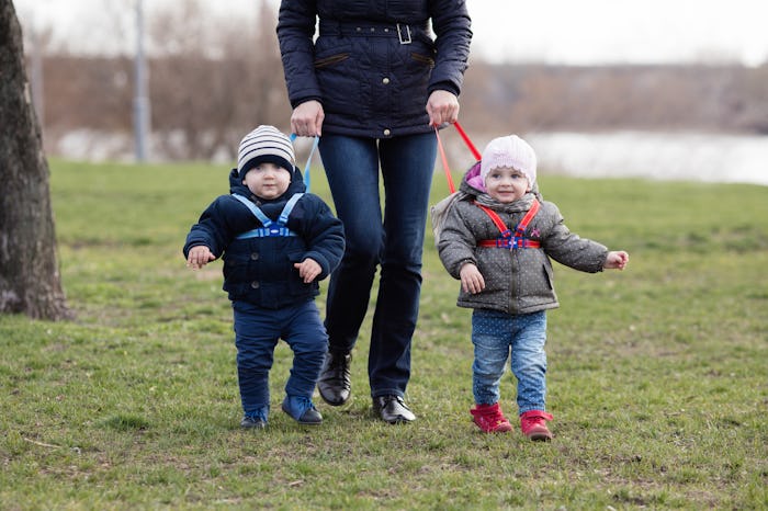 A mother walking her kids on a leash