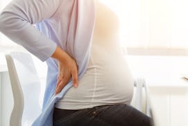 A pregnant woman experiencing hip pain during pregnancy with her hand on her hip