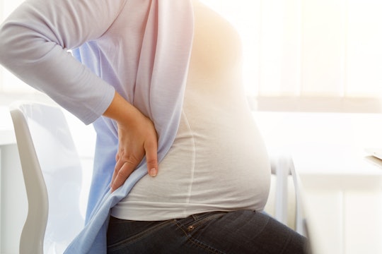 A pregnant woman experiencing hip pain during pregnancy with her hand on her hip
