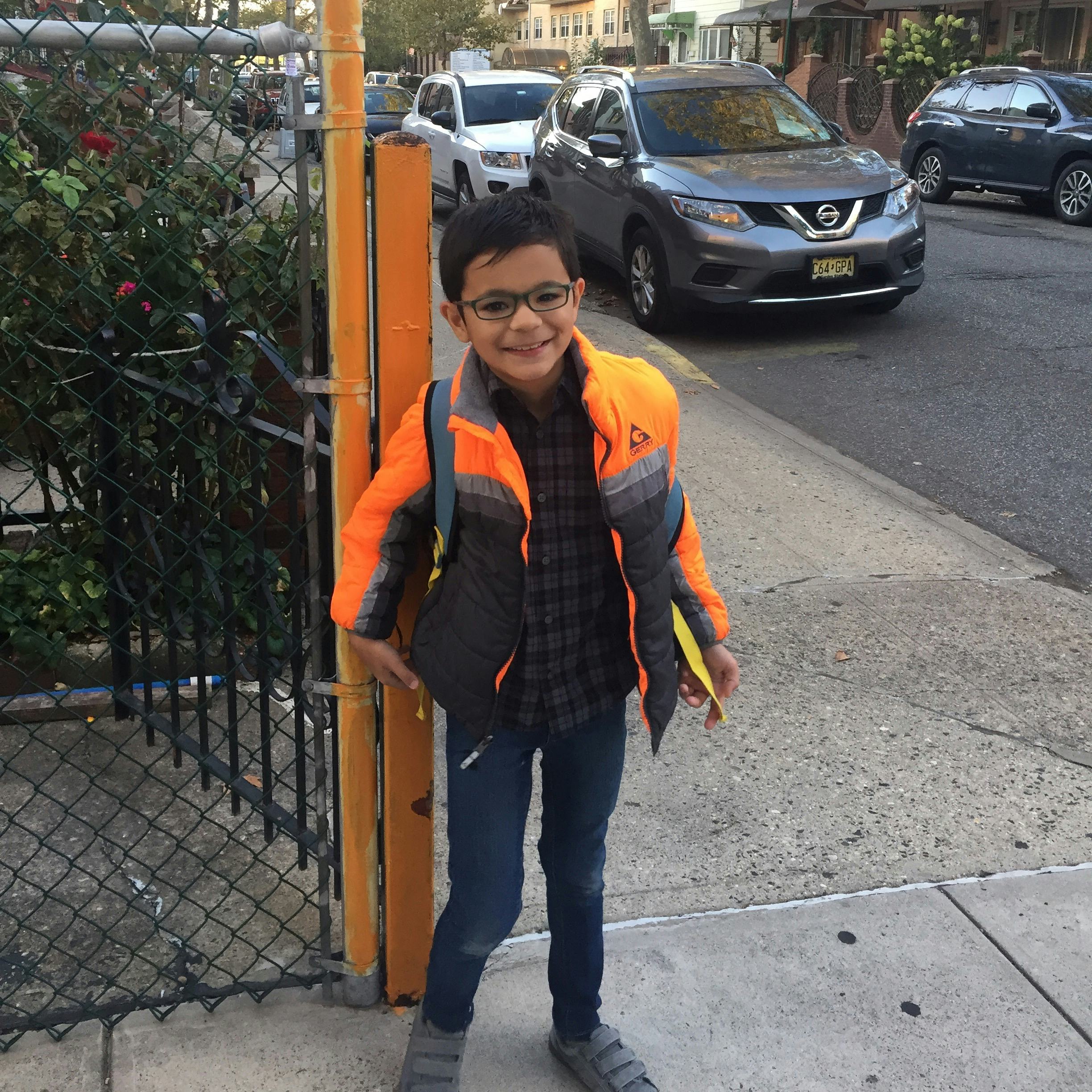 A boy with autism dressed for a school standing on the street