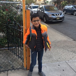 A boy with autism dressed for a school standing on the street