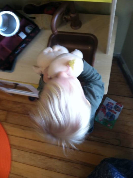 A blurred head of a blonde child holding a toy without its face being visible