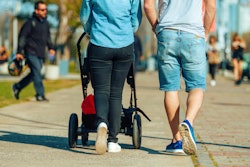 A woman pushing strollers while walking next to her partner
