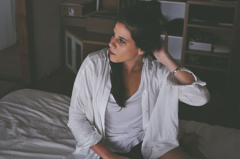 A woman in the white shirt sitting on the bed
