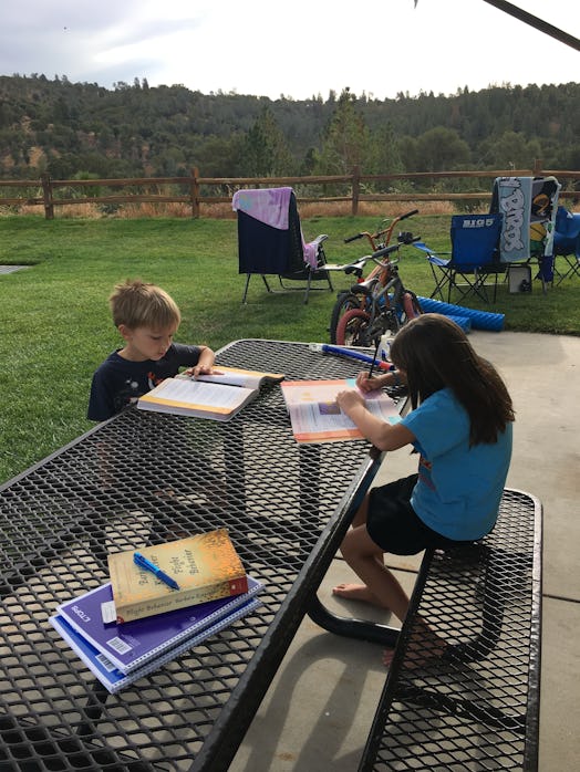 Two kids doing their homework in the backyard