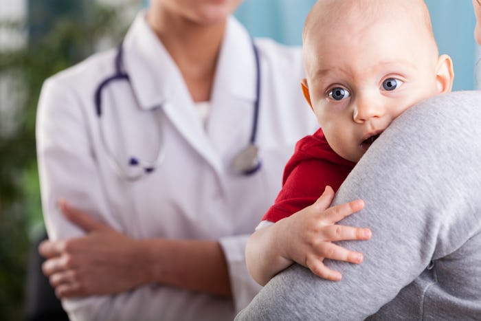 A mother holding her baby while talking to the doctor