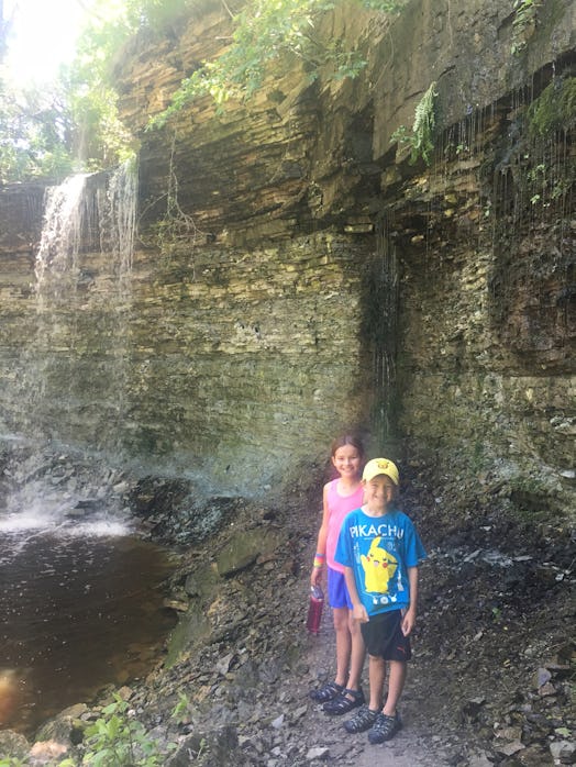 Two kids standing next to a small waterfall