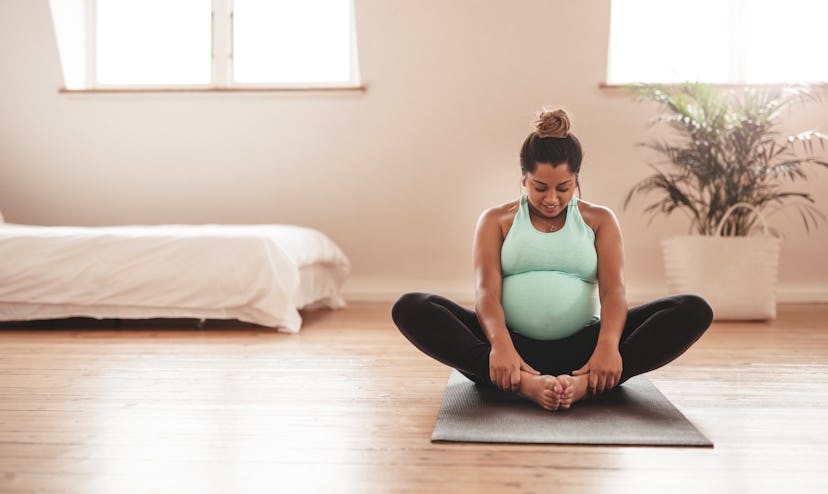 Pregnant woman sitting on the floor doing reformer pilates