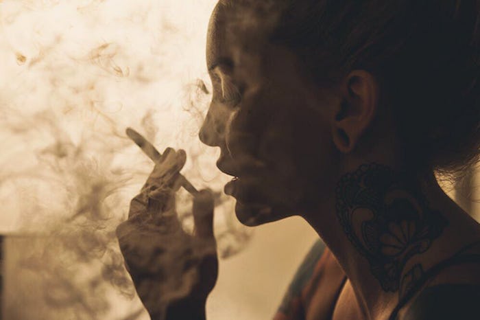 A mom holding a joint and exhaling smoke