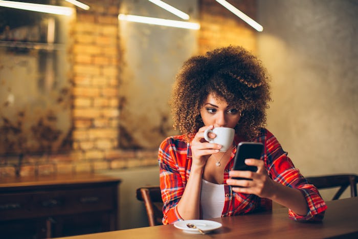 A curly-haired mom drinking coffee and networking with other moms on Instagram