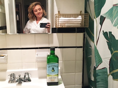A blonde woman that washed her face with olive oil for 2 weeks taking a photo in the mirror