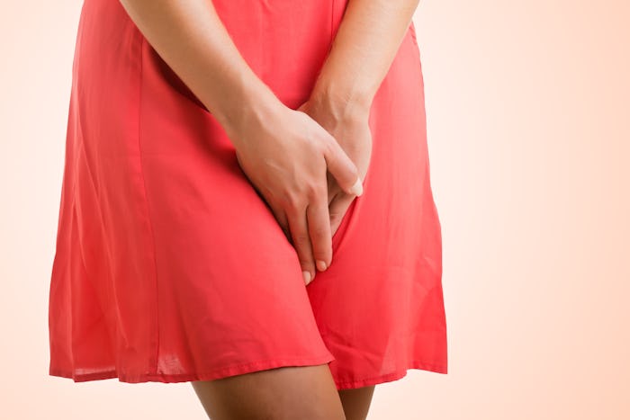 A woman in a red dress, holding her hands between her thighs during her ovulation