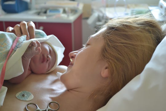 A mom looking down at her newborn on her chest