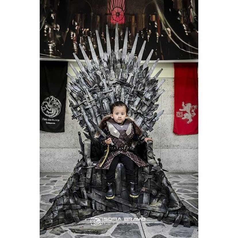 Baby wearing a Jon Snow outfit for Halloween and sitting on the throne from GoT