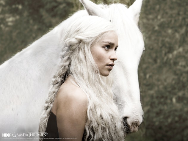 Daenerys Targaryen standing and holding her white horse