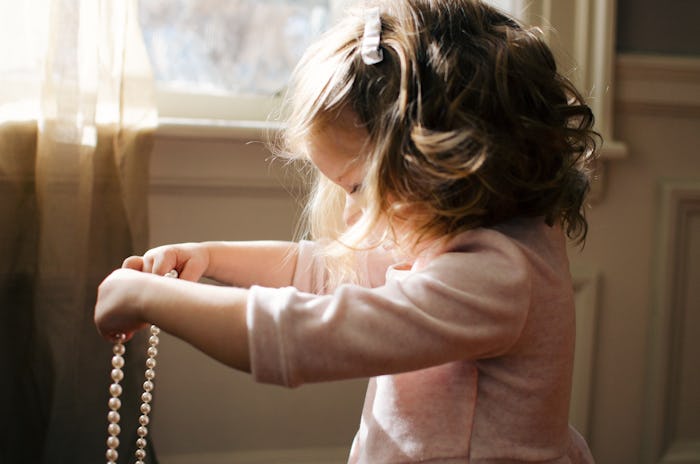 A little girl holding a pearl necklace